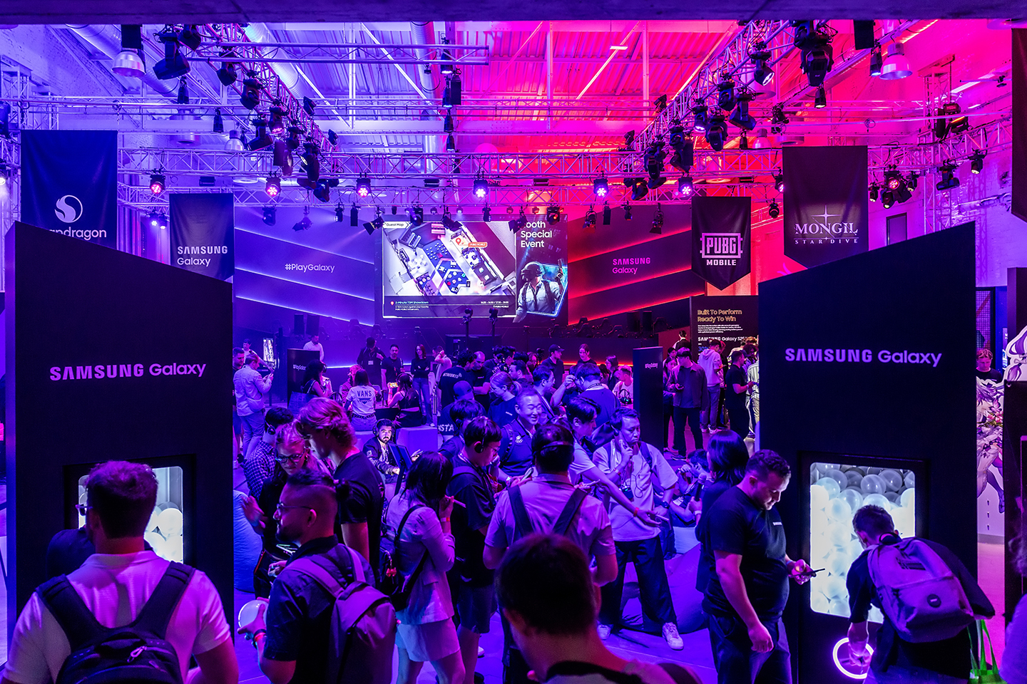 A wide shot of The World of PlayGalaxy event area demonstrates the large crowd and branded decorations.