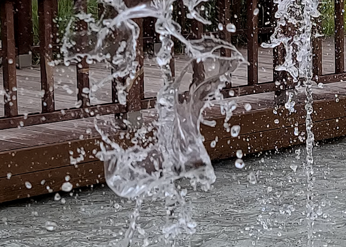 A still from a video of a splash of water in front of a boardwalk shows clear small details like water droplets due to better APV video file compression.