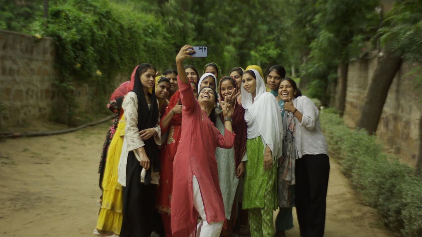 Soumya Dabriwal smiles while taking a selfie outside with participants of a community workshop.