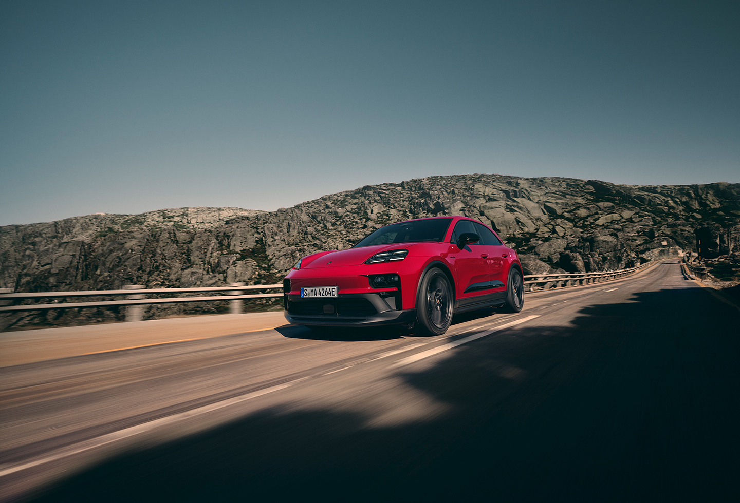 An image carousel features the 2026 Porsche Macan in Carmine Red and the Porsche Cayenne Electric in Mystic Green, both on the road. 
