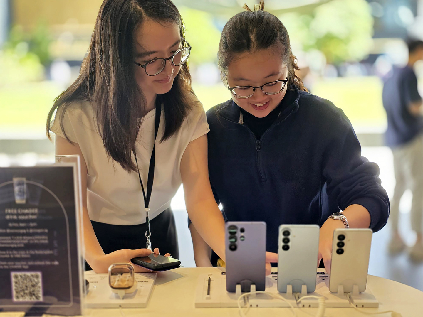Two people explore the Galaxy S26 series devices in different colors displayed on a table.