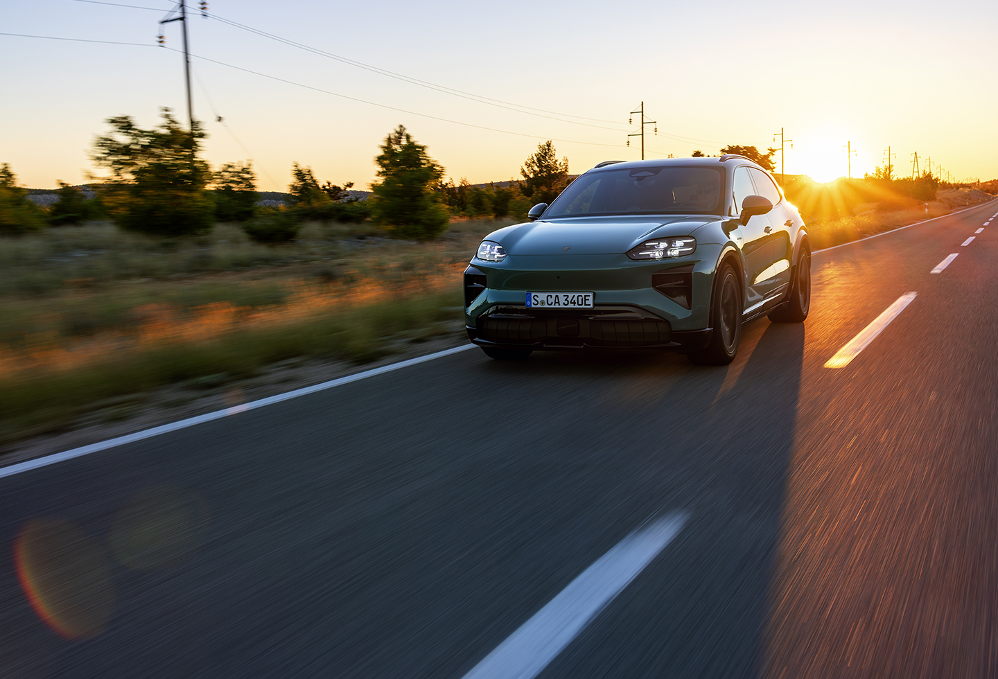 An image carousel features the 2026 Porsche Macan in Carmine Red and the Porsche Cayenne Electric in Mystic Green, both on the road. 