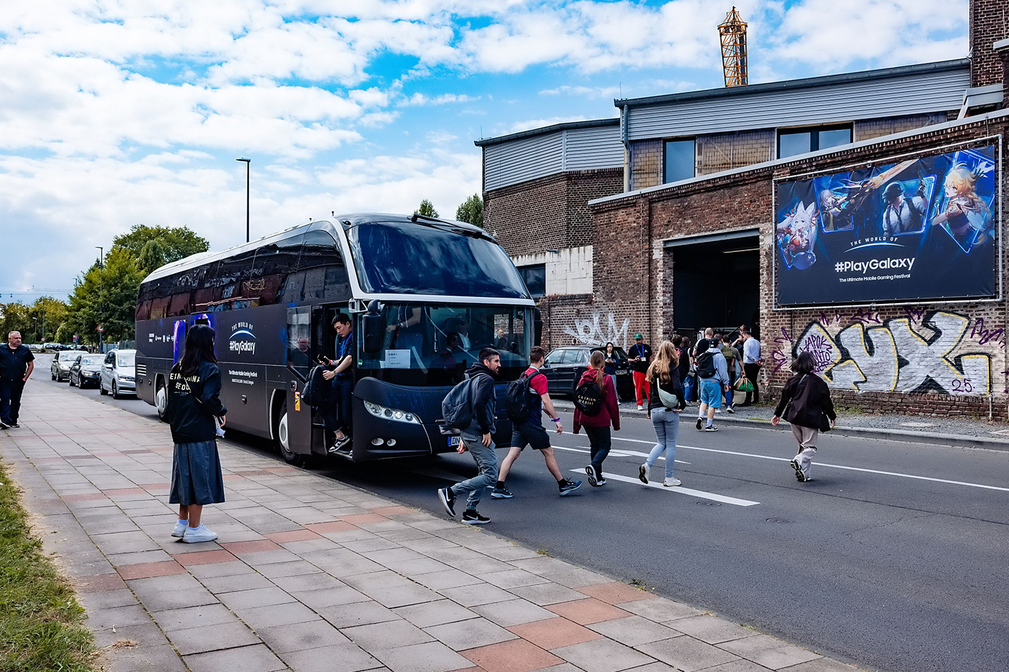 People are getting off a branded bus outside a building featuring The World of PlayGalaxy banner.